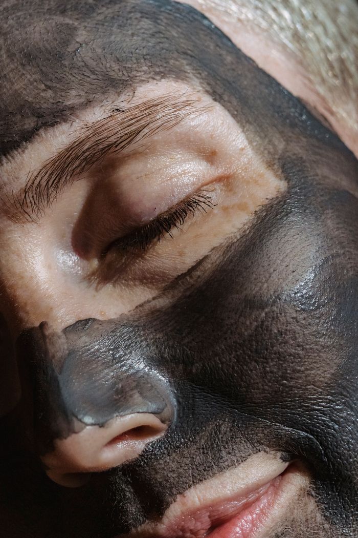 About Crop face of relaxing blond lady closing eyes with clay mask on face during beauty procedure